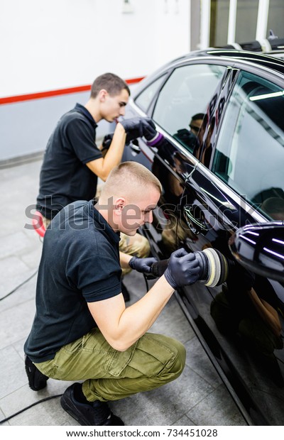 Car detailing - Workers with orbital polishers in auto\
repair shop. 