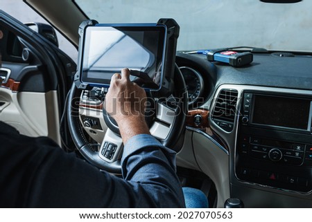 Car diagnostic. Technical inspection, car electronics. A Latin man holds a digitizing device.