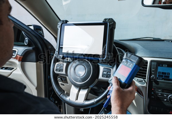 Car diagnostic. Technical\
inspection, car electronics. A Latin man holds a digitizing\
device.