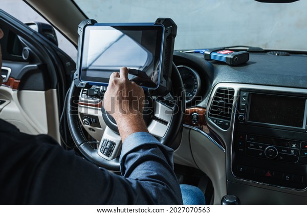 Car diagnostic. Technical\
inspection, car electronics. A Latin man holds a digitizing\
device.