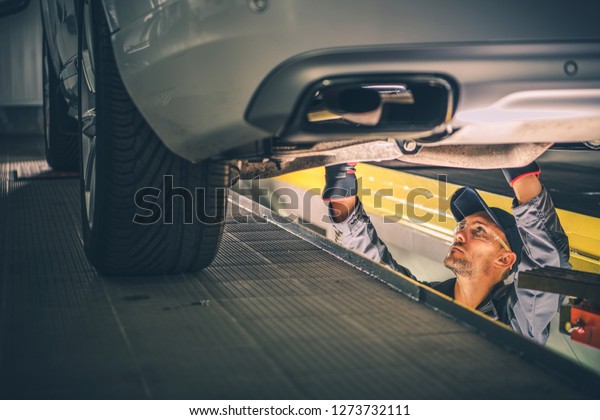 Car Diagnostic Technician Under the Vehicle.\
Automotive Industry.