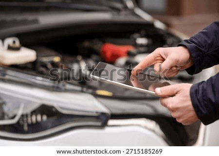 Car Diagnostic Test. Computer Diagnostics for Electric Car. Driving Test. Mechanic Serviceman using Scanner to Check Diagnose Car Problem.