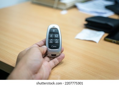 A car digital keyless in the people hand with office working desk as blurred background. Preparing for go back home after finish worked concept scene. Selective focus at the object.