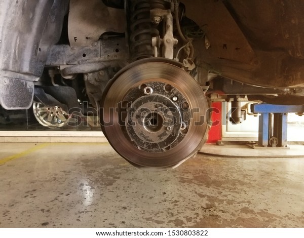 car disc brake during the wheel tire change or\
repair. Disc brake of the car during the maintenance at auto\
service garage.