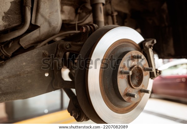 Car disc brake system. Car suspension in process\
of new tire replacement at garage workshop. Car disc brake mechanic\
check and repair. Disk break rotor. Car in change tire process at\
service station.