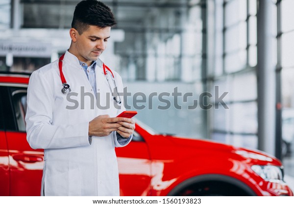 Car doctor with stethoscope in a car showroom\
talking on the phone