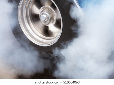 A car doing a burnout so that the tires spin smoke and smell of rubber.