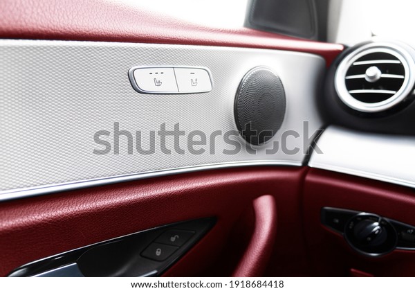 Car door handle inside the luxury\
modern car with red leather texture with stitching. Switch button\
control. Modern car interior details. Red perforated\
leather