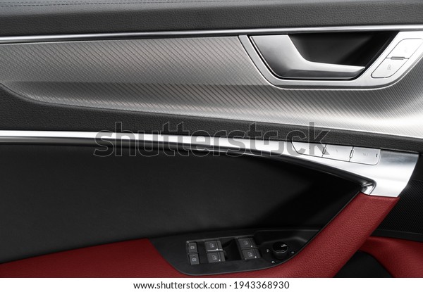 Car door handle inside the luxury\
modern car with red leather texture with stitching. Switch button\
control. Modern car interior details. Red perforated\
leather