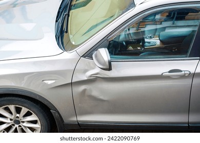 car door with large dent damage after road collision, view from above. Car body side damage, traffic accident. Dents on the car door. Bodywork concept
