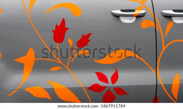 A car\
door painted with decorative plants and\
flowers