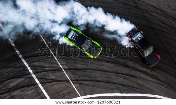 Car drift battle, Two car\
drifting battle on race track with smoke, Aerial view, Car\
drifting, Race drift car with lots of smoke from burning tires on\
speed track.