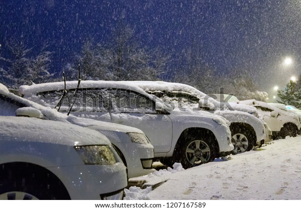 Car drifted with snow,\
snowfall in winter evening, Snow covered car after snowfall in\
night city.