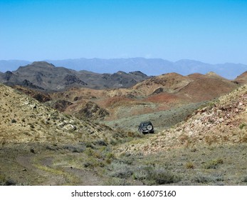 The car is driven off-road between the colored hills