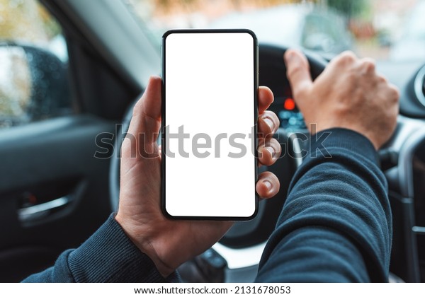 Car driver holding\
mobile smart phone over steering wheel, blank whgite screen as copy\
space, selective focus