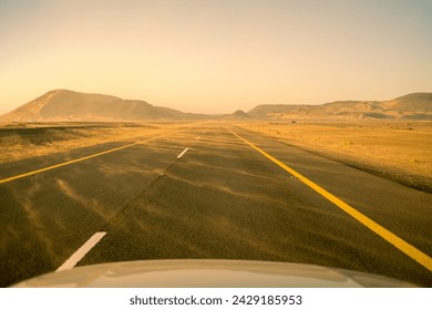 Car Driver POV: Traveling on asphalt highway road among desert during sand storm at sunset. Saudi Arabia. 
