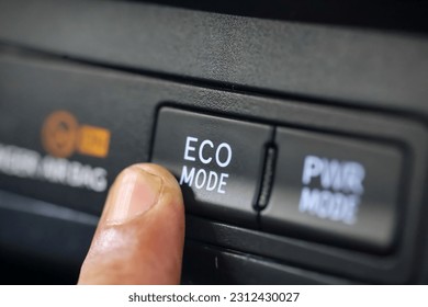 car driver pressing eco mode button on luxury car dashboard.  eco mode is a relaxed and fuel efficient driving mode