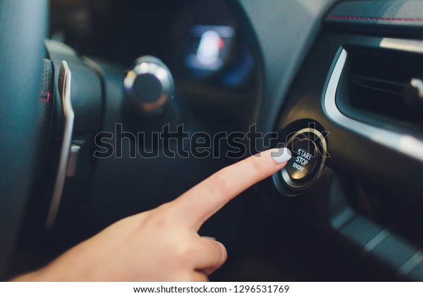 Car driver starting the engine keyless. Black.\
female hand.