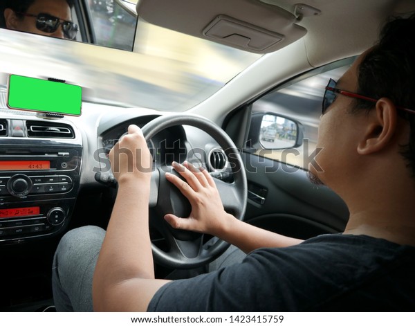 Car driver using smart phone on his\
dashboard, GPS map navigation, car sharing app\
concept