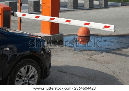 A car drives up to a barrier blocking the exit from the parking lot