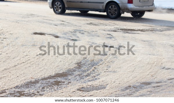 the\
car drives on wet and dirty asphalt on a winter\
road