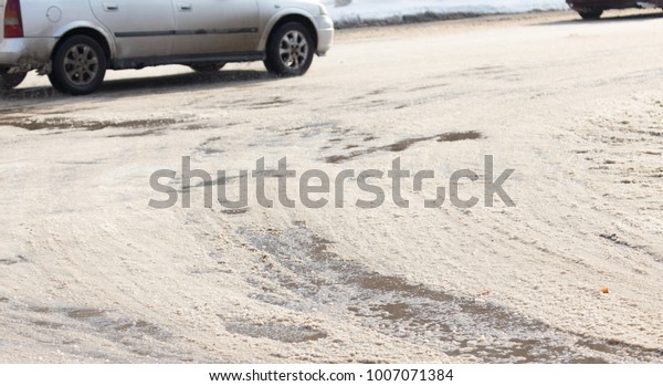 the
car drives on wet and dirty asphalt on a winter
road