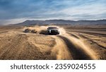 A car drives through a dusty desert, kicking up dust. An off road car driving on the desert 