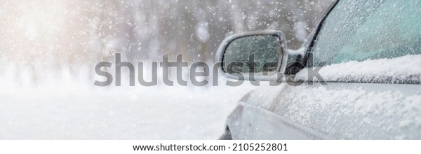 The car drives through the\
snow, the bright winter sun shines against the background of the\
forest. Close-up rearview mirror. The vehicle is covered with snow.\
Snowing.