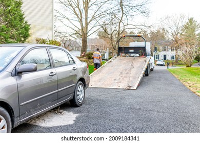 Car In Driveway With Tower Man Working To Tow Vehicle Due To Fuel Leak That Damaged Pavement Covered In Cat Litter To Absorb The Gas