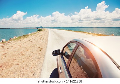 Car Driving Across Ocean By The Road