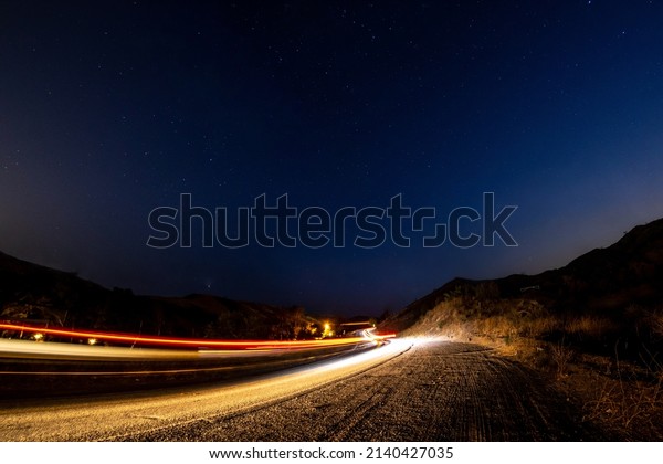 Car driving up dark\
road under the stars