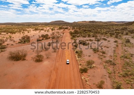 Car driving down a dusty red earth road in outback Australia