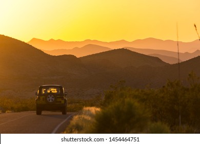 A Car Driving Down The Road In Big Bend National Park During A Beautiful Sunset In Texas.