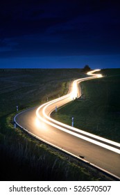 Car Driving Down A Winding Country Road, Long Exposure, Head Lights In Blurred Motion