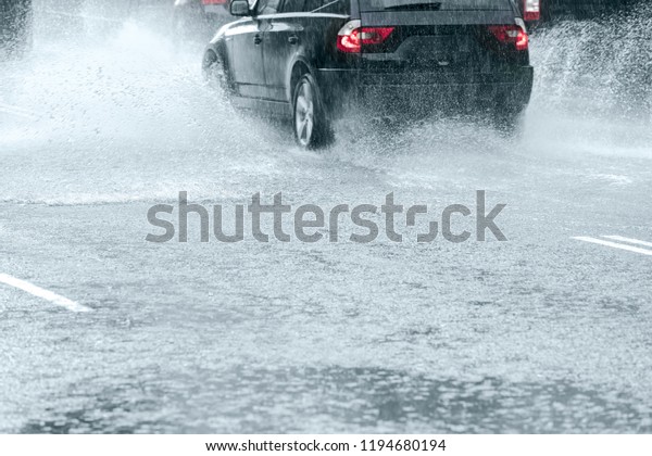 car driving In high speed through\
big water puddle during heavy rain making water\
splashes