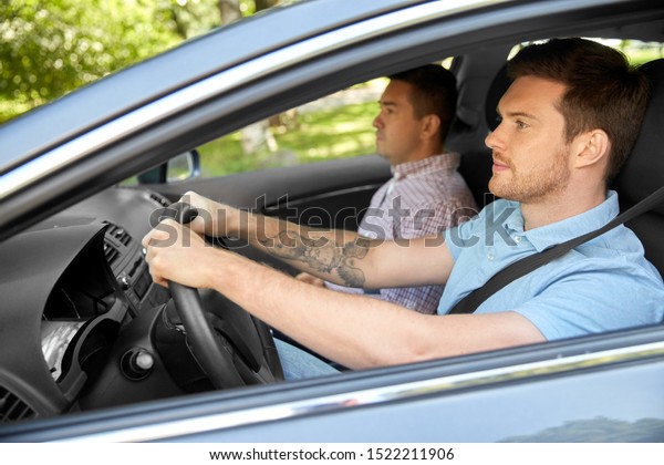 car driving lesson and carpooling\
concept - instructor on passenger seat and young\
driver