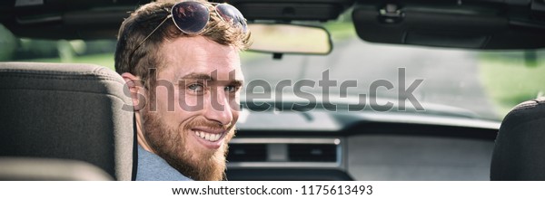 Car driving man driver smiling portrait. Young\
adult sitting in front seat of new convertible sports car.\
Panoramic header crop\
banner.
