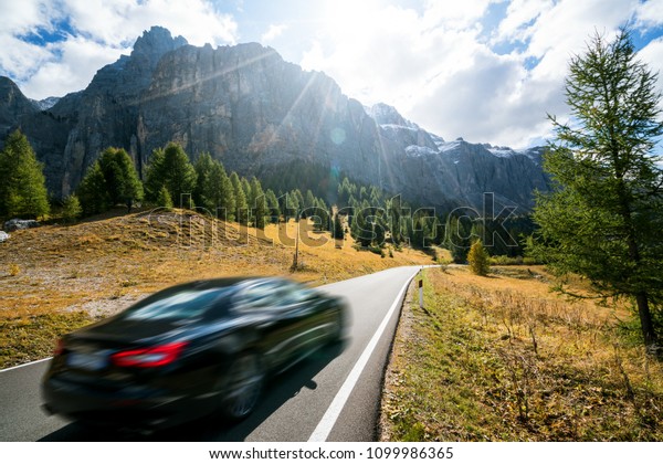 Car\
driving on beautiful mountain road with trees, forest and mountains\
in the backgrounds. Taken at state highway road in Passo Gardena,\
Sella mountain group of Dolomites mountain in\
Italy.