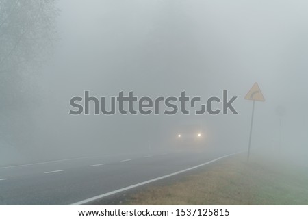 Car driving on a country road in bad visibility conditions - foggy weather 