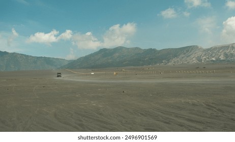 A car is driving on a dirt road in a desert. The sky is clear and the sun is shining brightly - Powered by Shutterstock