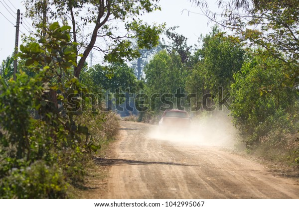 Car driving on dirt road\
with dust