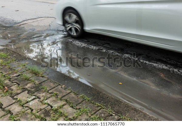 Car driving on a flooded road, Concrete asphalt\
cracks on the Street, Line rough surface and grey cracked asphalt\
road, Wheels ran over the\
water