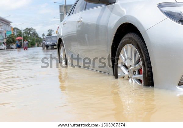 Car driving on a flooded road, The broken car is\
parked in a flooded road.