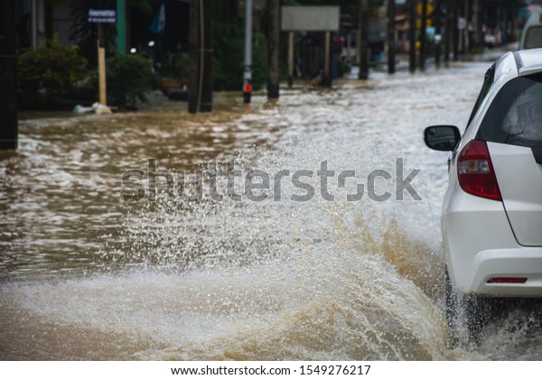 Car driving on\
flooded road with Flood water flow through the road after heavy\
winds and storm surges.
