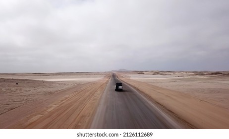 Car driving on gravel road in aerial desert. Sandy landscape, nobody. Wildlife, mountains. Nature in Namibia, Africa. Highway to Skeleton coast. SUV white automobile vehicle.