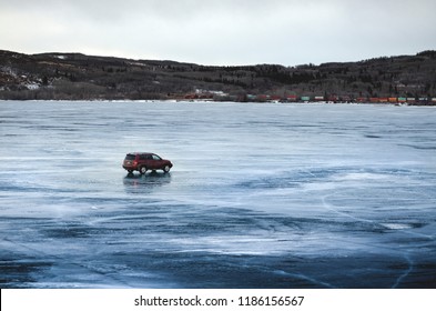 A Car Driving On The Ice Of Frozen Ghost Lake In Alberta, Canada.