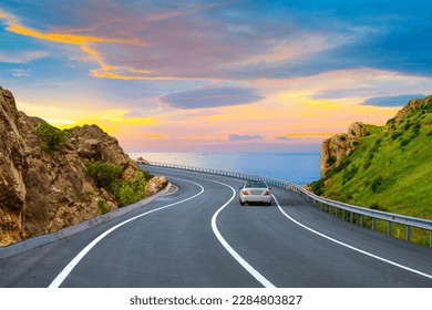 Car driving on the road in summer. highway landscape at colorful sunset. coastal road in europe. summer trip on the road on beautiful nature scenery. highway view on ocean beach.