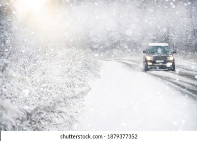 The car is driving on a winter road in a blizzard