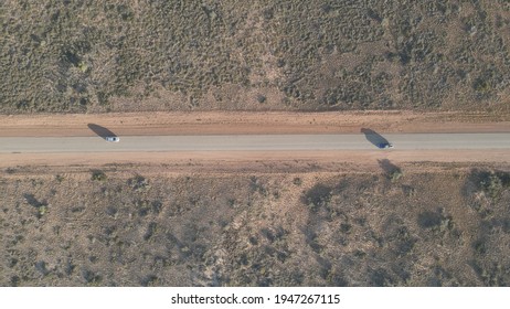 Car Driving Over Rural Road In The Australian Desert With A Long Shadow During Golden Hour In Exmouth, Western Australia. Top Aerial Shot