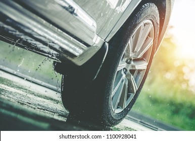 Car Driving in the Rain. Modern Rain Summer Season Tires on the Wet Pavement. Closeup Aquaplaning Photo.
